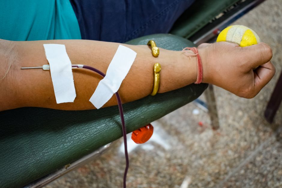 A person donating blood at a clinic while discussing medication use with staff