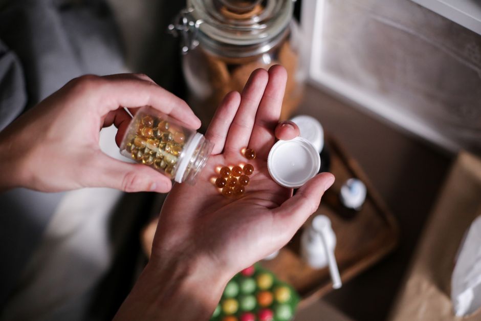 Assortment of vitamin supplements and pill bottles next to oxycodone medication representing potential drug interactions