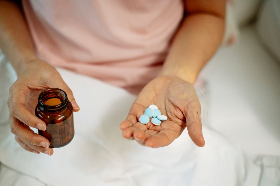 Oxycodone pill bottle on a nightstand next to a glass of water at night