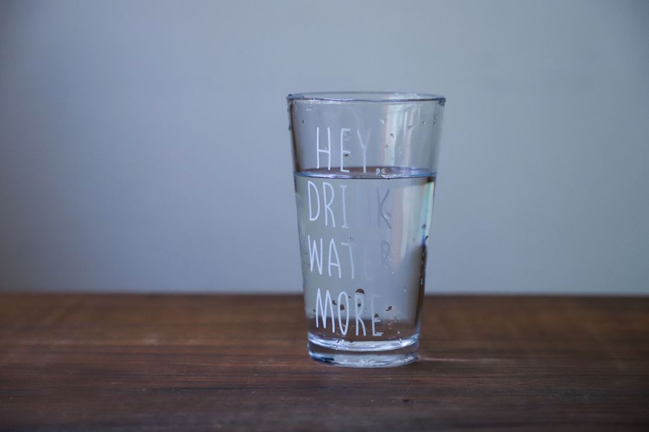 Person drinking a glass of water to stay hydrated while wondering if it helps clear oxycodone from the body
