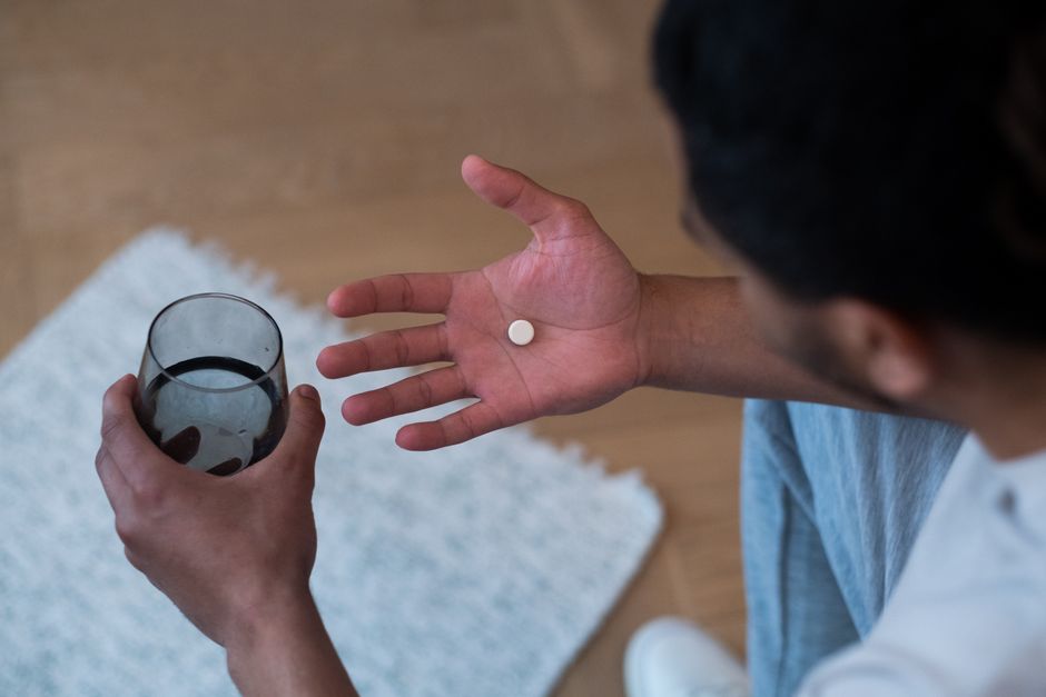 Person holding oxycodone pill bottle near car keys, illustrating driving safety concerns after taking oxycodone