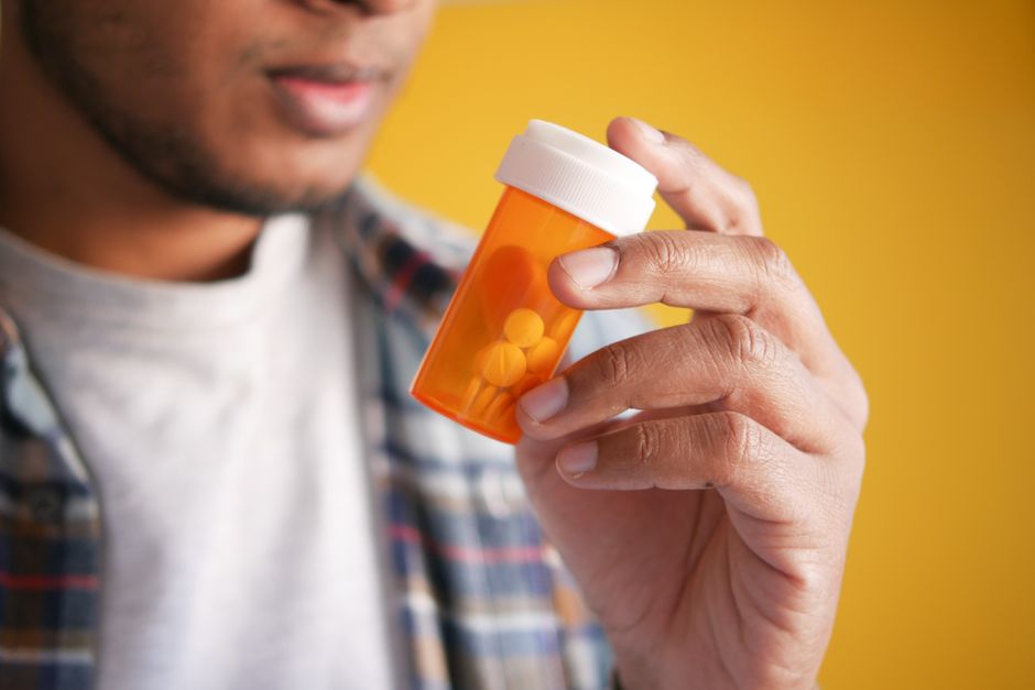 Person looking anxious while holding a prescription pill bottle of oxycodone