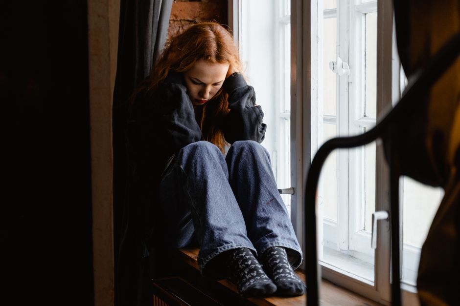 Person sitting on a bed looking anxious and overwhelmed during oxycodone withdrawal