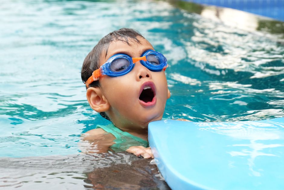 Person standing at edge of swimming pool considering safety risks of swimming while taking oxycodone
