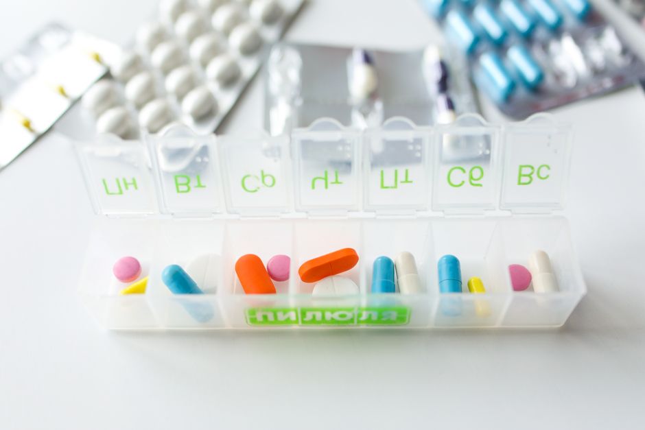 Clock and pill organizer representing the best time to take oxycodone for pain relief