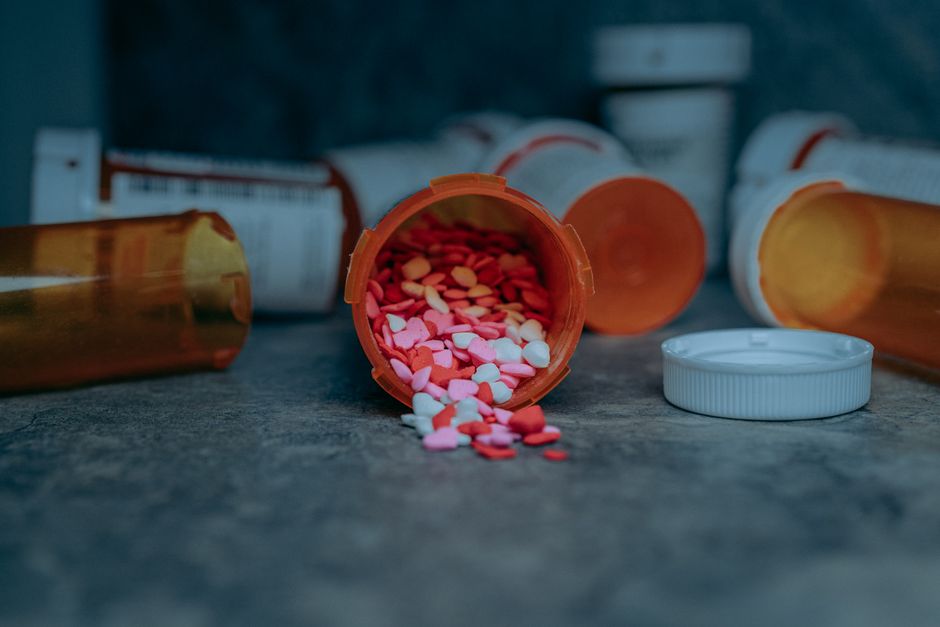 Different strengths of oxycodone tablets spilled next to a prescription bottle