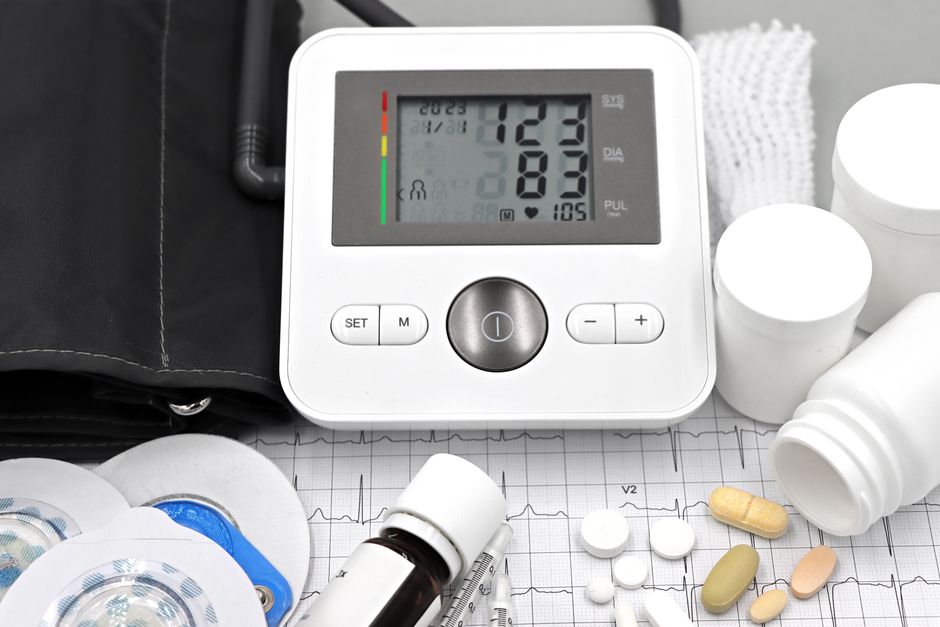 Person checking blood pressure with a monitor next to oxycodone pain medication