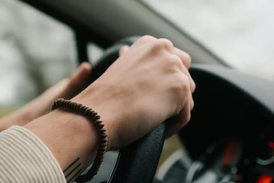 Person holding a pill bottle while sitting in the driver's seat of a car, illustrating the risks of driving after taking oxycodone